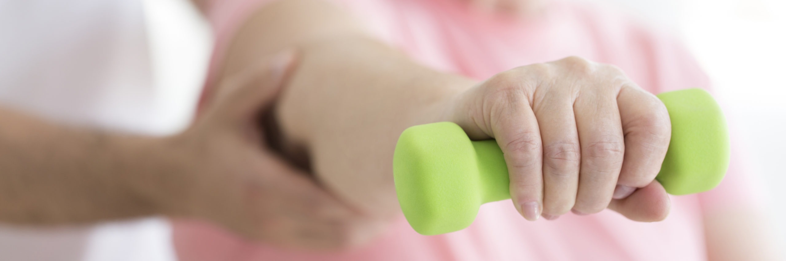 Close-up of person holding green dumbbell during fitness for seniors classes