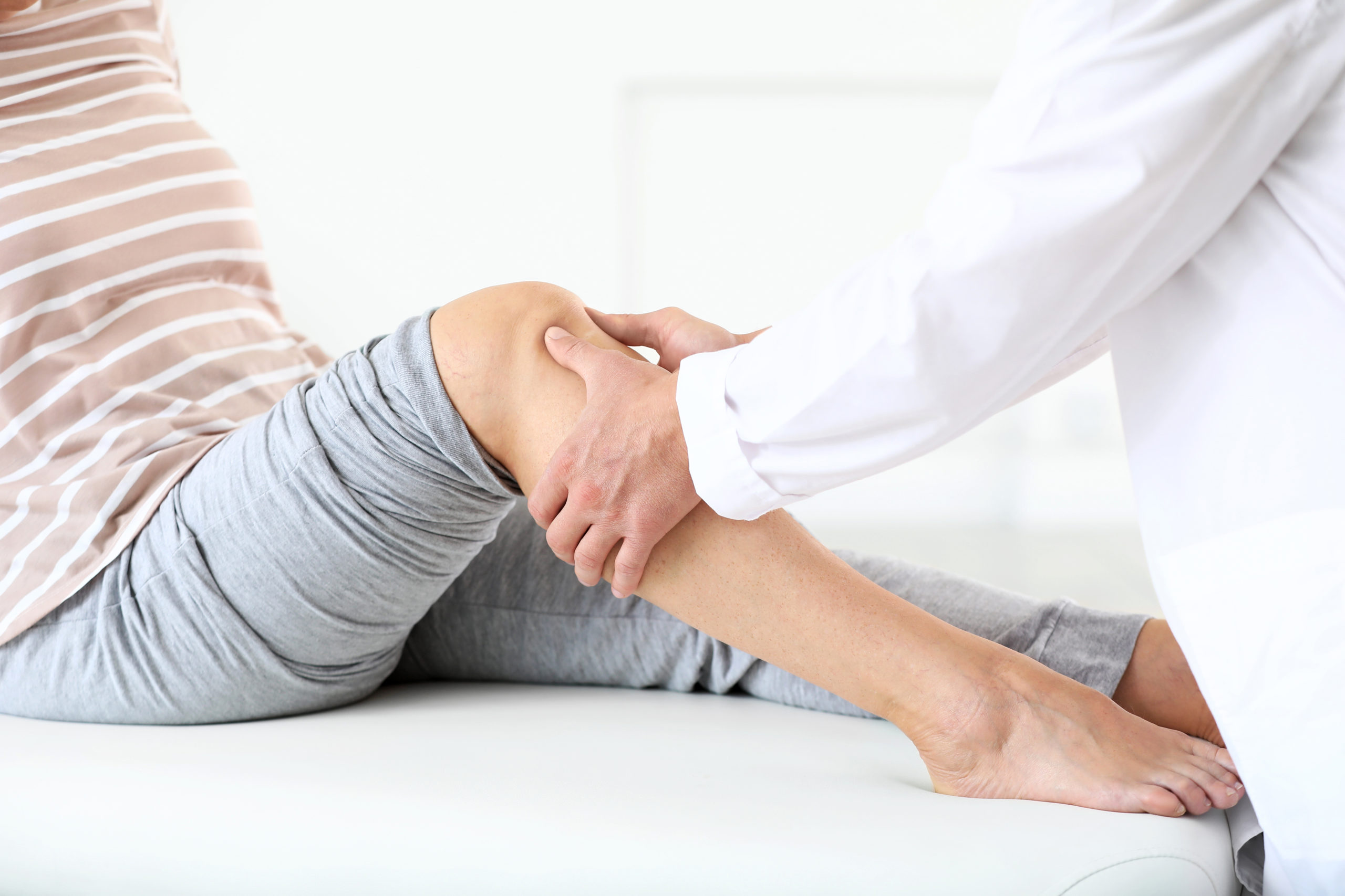 Doctor examining mature woman with joint pain in clinic