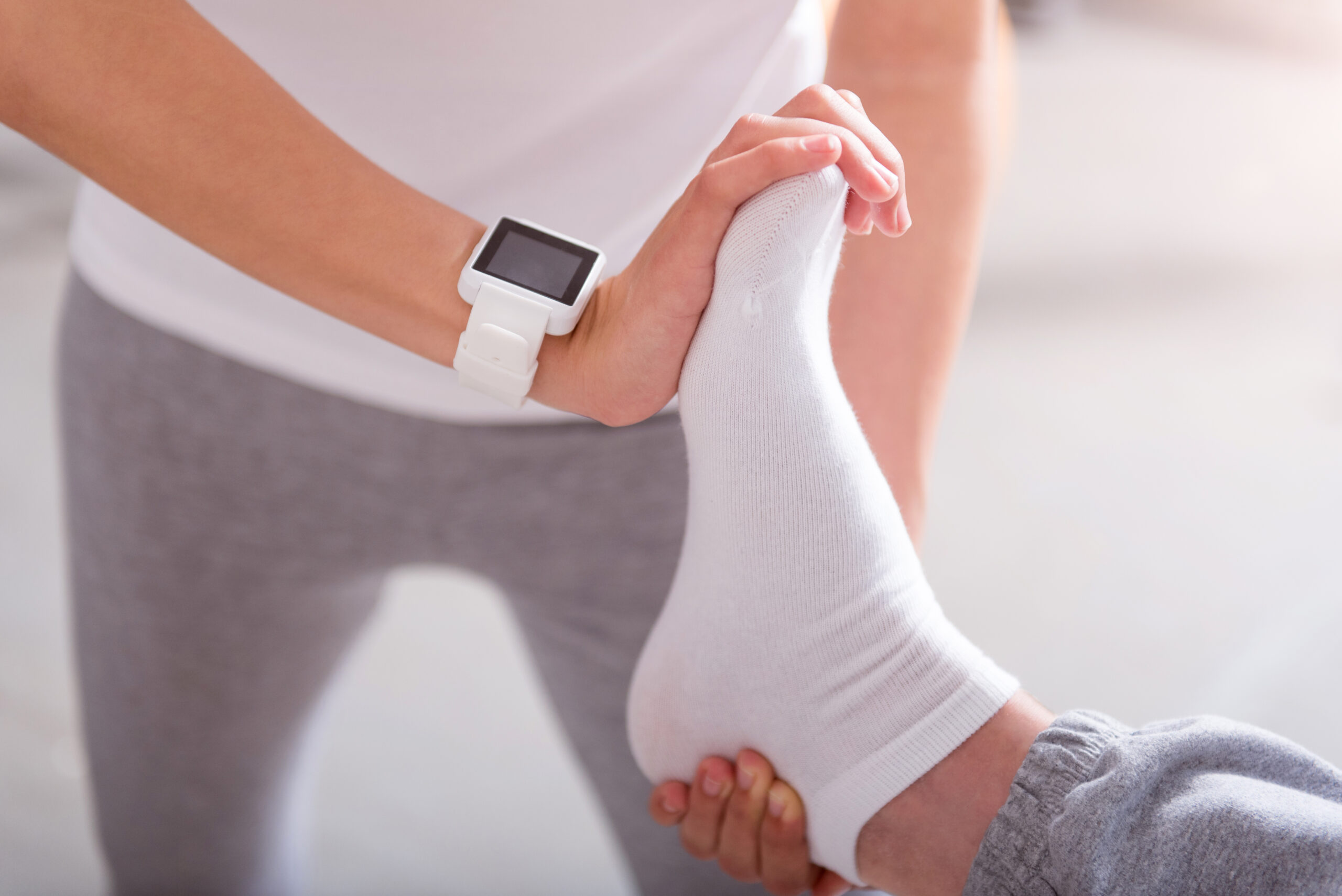 Stretch exercise. Close up of hands of physiotherapist stretching patient sole in a medical office