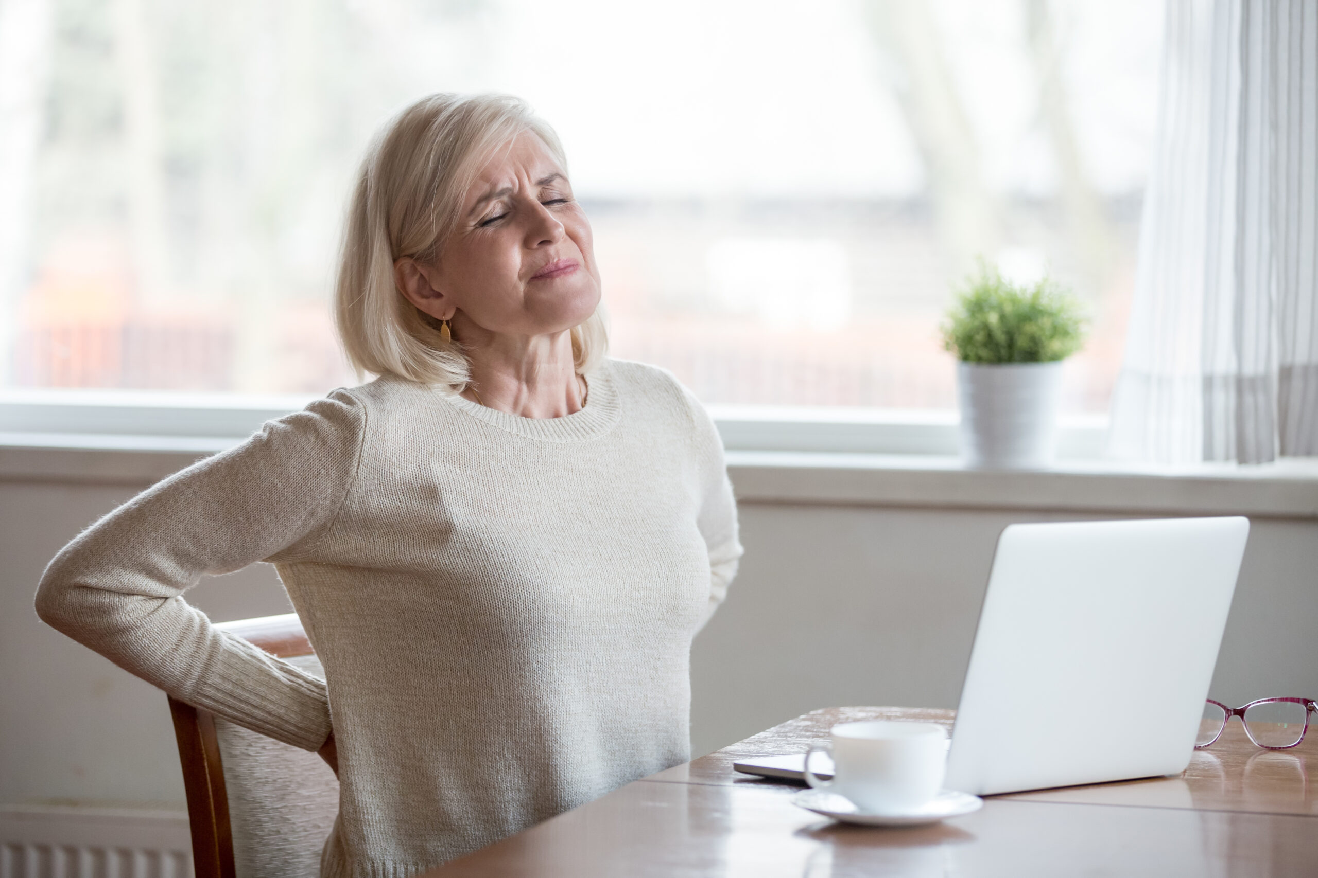 Upset mature middle aged woman feels back pain massaging aching muscles, sad senior older lady suffers from low-back lumbar pain sitting in incorrect sedentary posture, backache radiculitis concept