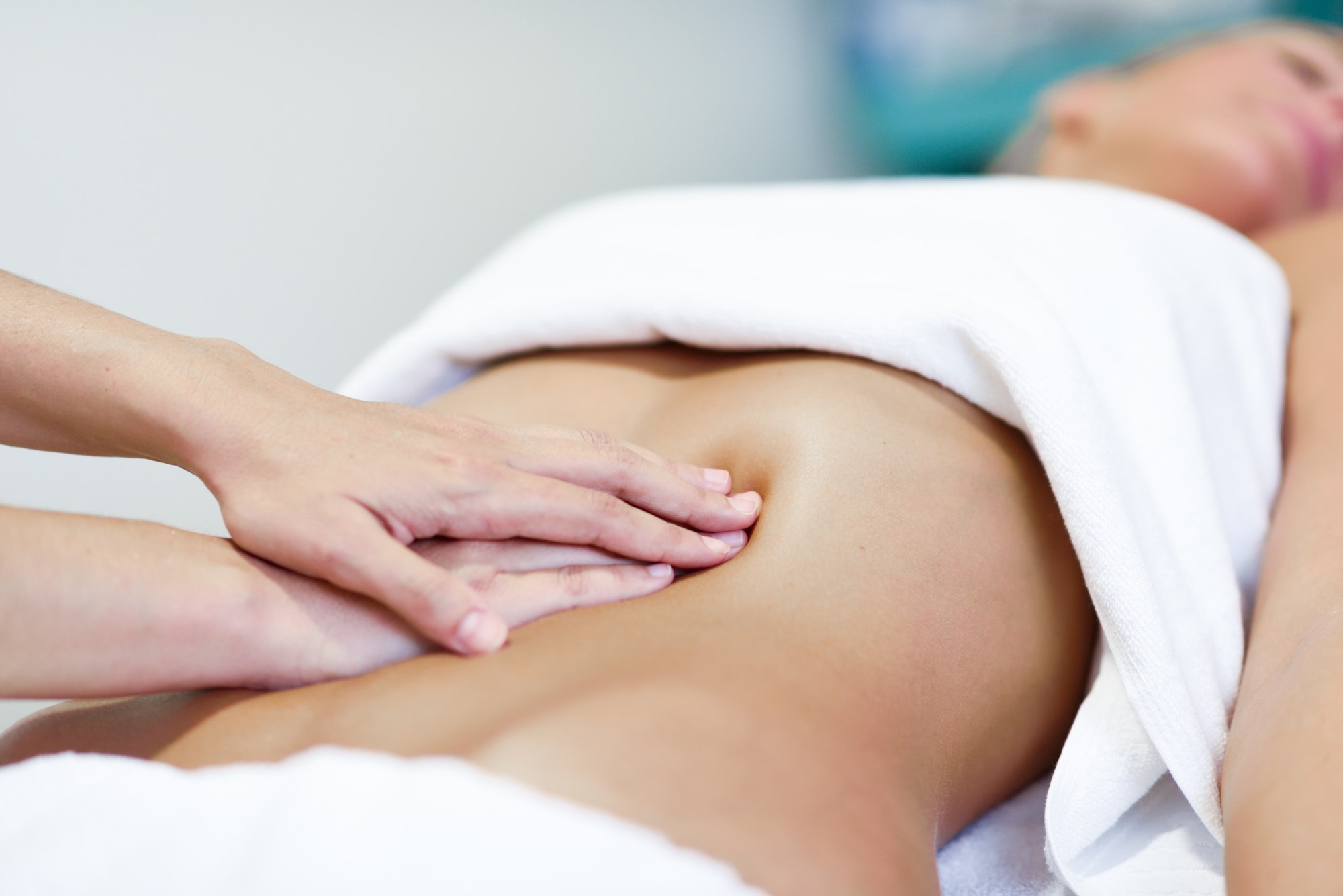 Hands massaging female abdomen.Therapist applying pressure on belly. Woman receiving massage at spa salon